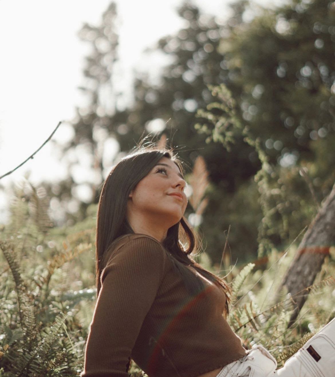 Foto de Paola Díaz Álvarez. Vemos su perfil. Se encuentra sentada en la grama mirando hacia arriba. 