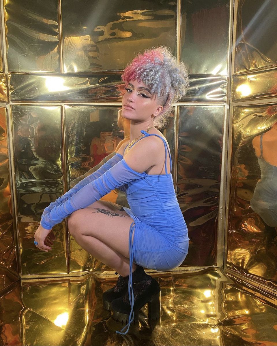 Imagen de Joan Correa Santiago posando frente a una pared dorada que refleja la luz. 