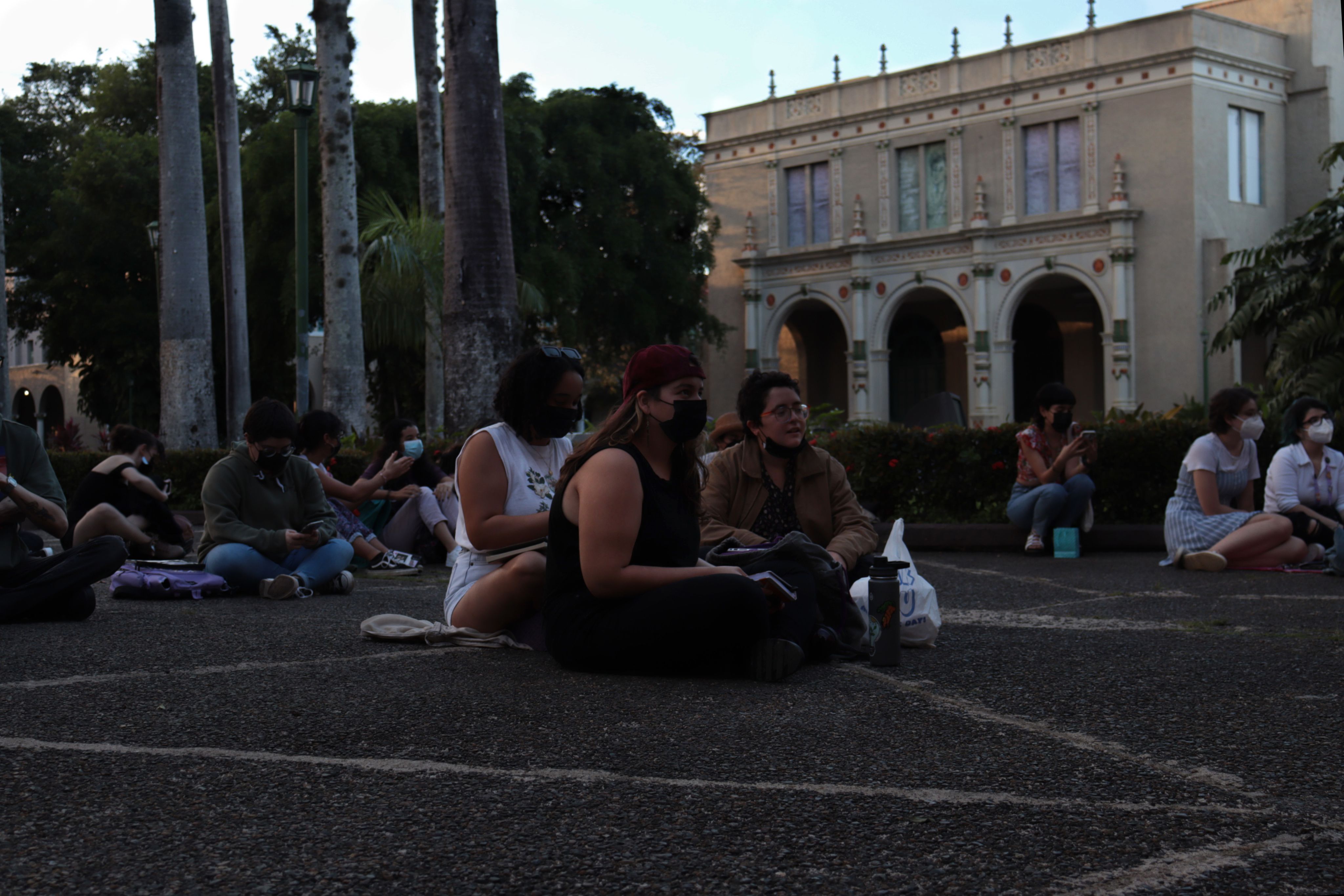 Grupo de tres estudiantes sentadas frente al teatro de la IUPI.