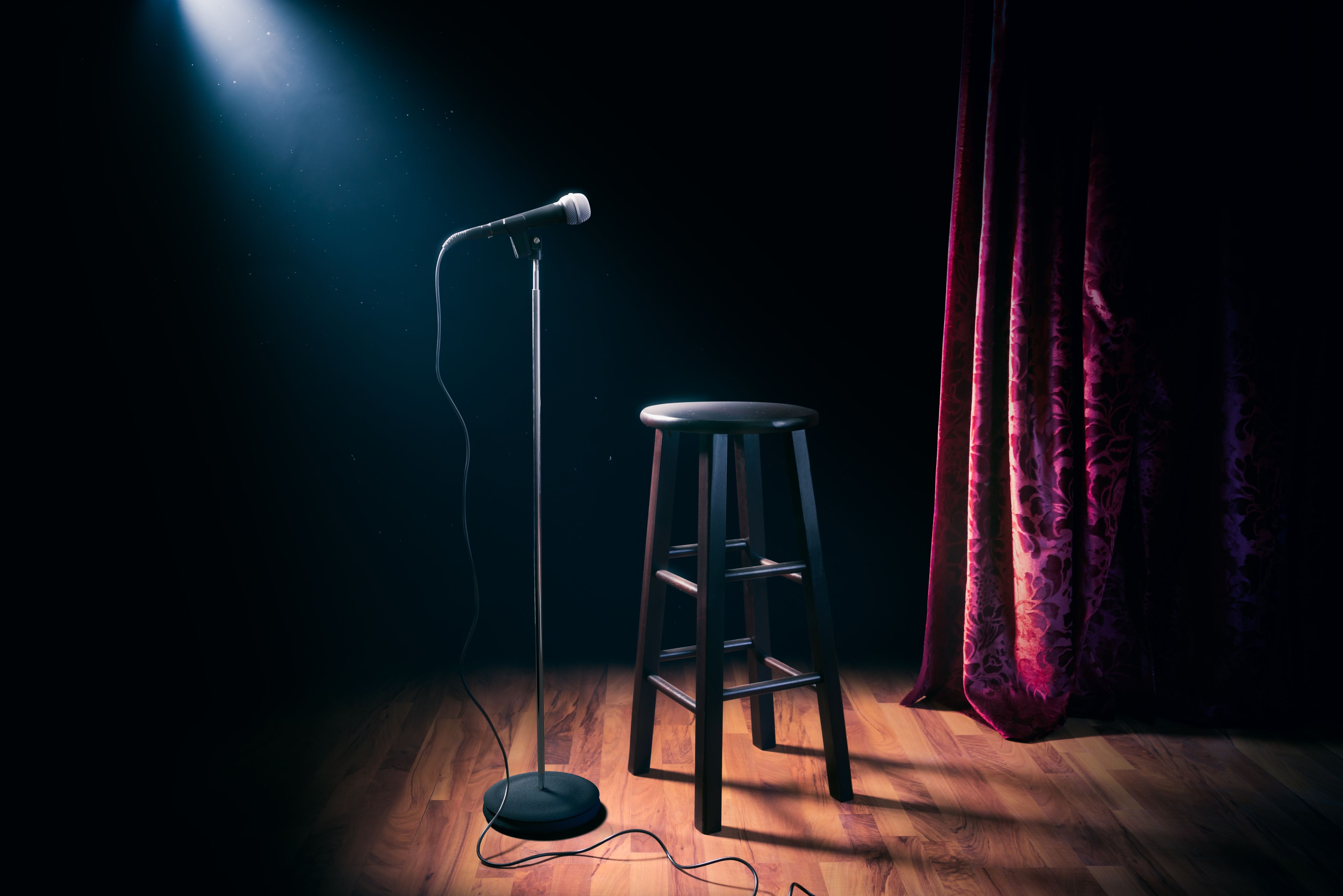 Asiento de madera y micrófono en tarima de un teatro.